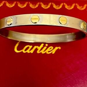A white gold bangle featuring yellow gold screws in 14k solid gold .